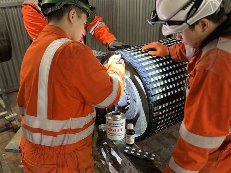 Workers installing HUAYE-CRL-15 ceramic rubber composite pulley lagging on coal mine conveyor drive pulley onsite